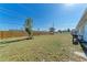 Large grassy backyard featuring a wood fence, a mature tree, and a clear blue sky, offering ample space at 1777 Pomelo Dr, Venice, FL 34293