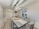 Dining room with modern light fixture, gray wood floors and table, with kitchen visible in the background at 1777 Pomelo Dr, Venice, FL 34293