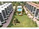 Aerial view showing resort-style pool, lush landscaping, and condo buildings at 8701 Midnight Pass Rd # 106A, Sarasota, FL 34242