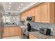 Modern kitchen featuring wood cabinets, granite countertops, and stainless steel appliances at 8701 Midnight Pass Rd # 106A, Sarasota, FL 34242
