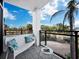 Relaxing balcony with white couch and a view of palm trees at 4241 Gulf Of Mexico Dr # 202, Longboat Key, FL 34228