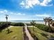 Walk to the beach via a paved pathway, lush landscaping, and palm trees at 4241 Gulf Of Mexico Dr # 202, Longboat Key, FL 34228