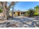 Charming yellow house with a metal roof, surrounded by lush landscaping at 563 Juan Anasco Dr, Longboat Key, FL 34228