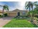 One-story home with a tan exterior, lush landscaping, and a brick driveway at 8912 Heritage Sound Dr, Bradenton, FL 34212