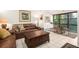 Spacious living room featuring a brown leather sofa and ample natural light from large windows at 1704 Pelican Cove Rd # T138, Sarasota, FL 34231