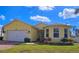 Charming yellow single-story home with a well-manicured lawn and attached two car garage at 1877 Dragonfly Ave, North Port, FL 34288