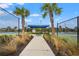 Well-maintained tennis courts with shaded seating area at 2724 Butterfly Jasmine Trl, Sarasota, FL 34240