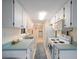 Galley kitchen with white cabinets, teal countertops, and a window at 300 Coral Rd, Venice, FL 34293