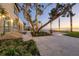 Inviting backyard featuring a stone patio, mature tree, and tranquil waterfront scenery at dusk at 4311 Bay Shore Rd, Sarasota, FL 34234