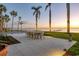 Serene backyard with a dining set, pool, lush landscaping, and picturesque waterfront views at sunset at 4311 Bay Shore Rd, Sarasota, FL 34234