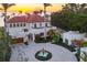 Stunning waterfront estate featuring a terracotta roof, circular driveway with fountain, and lush tropical landscaping at sunset at 4311 Bay Shore Rd, Sarasota, FL 34234