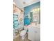Clean bathroom with teal walls, white vanity, and a tropical shower curtain at 1323 Mediterranean Dr # 111, Punta Gorda, FL 33950