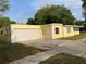 Charming yellow home featuring an attached garage with a large driveway and beautiful tree in the background at 1630 29Th St, Sarasota, FL 34234