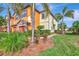 Townhouse exterior with orange and beige paint, landscaping, and palm trees at 20223 Lagente Cir, Venice, FL 34293