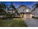 Two-story house with beige siding, gray door, and landscaped yard at 7000 Marina Dr, Holmes Beach, FL 34217