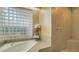 Relaxing bathroom with soaking tub, glass block window, and walk-in shower at 1965 White Feather Ln, Nokomis, FL 34275