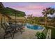 Relaxing poolside patio with seating, umbrella, and a beautiful sunset view at 4817 Ocean Blvd, Sarasota, FL 34242