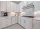 Modern white kitchen with stainless steel appliances and gray herringbone backsplash at 7675 Summerland Cv, Bradenton, FL 34202