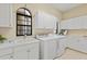 Bright laundry room features white cabinets, sink, and modern washer and dryer appliances at 3769 Caledonia Ln, Sarasota, FL 34240
