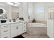 Elegant bathroom with white vanity, soaking tub, and neutral tile flooring at 4820 Coastal Days Ln, Bradenton, FL 34211