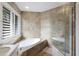 Bathroom showcasing soaking tub with tile surround and a glass-enclosed shower at 4946 Brywill Cir, Sarasota, FL 34234