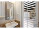 Bathroom with white sink, stone countertops and floors, framed mirror, and window with shutters at 4946 Brywill Cir, Sarasota, FL 34234