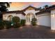 Stunning home exterior with a tile roof, arched entryway, beautiful landscaping, and a brick driveway at 4946 Brywill Cir, Sarasota, FL 34234