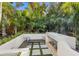 Outdoor fireplace with a built-in bench, surrounded by tropical landscaping and pavers at 4946 Brywill Cir, Sarasota, FL 34234