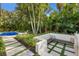 Outdoor fireplace with a built-in bench, surrounded by tropical landscaping and pavers, near pool at 4946 Brywill Cir, Sarasota, FL 34234