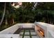 Outdoor fireplace and seating area with comfortable pillows, surrounded by beautiful tropical landscaping at 4946 Brywill Cir, Sarasota, FL 34234