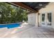 Outdoor pool with travertine patio, palm trees, and a covered lanai with ceiling fan and outdoor furniture at 4946 Brywill Cir, Sarasota, FL 34234