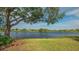 Serene lakefront view with lush landscaping and mature tree at 6525 Berkshire Pl, University Park, FL 34201