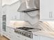 Gourmet kitchen featuring stainless steel appliances, a modern range hood, stylish backsplash, and white cabinetry at 8367 Sea Glass Ct, Sarasota, FL 34240