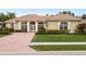 Tan house with tile roof, brick driveway & lush landscaping at 359 Turtleback Xing, Venice, FL 34292