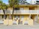 Two-story yellow condo building with balconies, palm trees, and white lattice fencing at 5955 Midnight Pass Rd # 4E, Sarasota, FL 34242