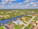 Wide aerial showcasing waterfront home, solar panels, and lush landscape at 9150 Melody Cir, Port Charlotte, FL 33981