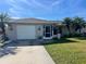 Single-story home with a white garage door, landscaping, and driveway at 9359 Casa Grande Ave, Englewood, FL 34224