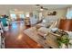 Open living room with hardwood floors, L-shaped sofa, and views into dining area at 9359 Casa Grande Ave, Englewood, FL 34224