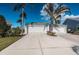 Two-car garage with additional parking and tropical landscaping at 1005 Ibis Ct, Bradenton, FL 34209