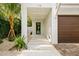 Front entry with walkway, modern door, and brown garage doors at 112 Maple Ave, Anna Maria, FL 34216