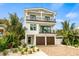 Two-story home with a white exterior, brown garage doors, and palm trees at 112 Maple Ave, Anna Maria, FL 34216