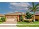 Tan house with beige garage door, landscaping, and paver driveway at 11786 Sistine Ln, Venice, FL 34293