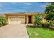 Tan house with beige garage door, landscaping, and paver driveway at 11786 Sistine Ln, Venice, FL 34293