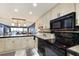Open kitchen with white cabinets, black appliances, and views to living area at 1510 1St W Ave # 504, Bradenton, FL 34205