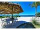 Beachfront patio with thatch umbrellas and white chairs providing shade at 367 Compass Point Dr # 201, Bradenton, FL 34209