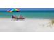 Two lounge chairs under an umbrella on a sunny beach at 411 S Casey Key Rd, Nokomis, FL 34275