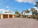 Double-car garage with wooden doors and paver driveway at 411 S Casey Key Rd, Nokomis, FL 34275
