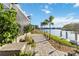 Picturesque waterfront backyard with lush greenery and paved path leading to the dock at 1111 Socorro Dr, Punta Gorda, FL 33950
