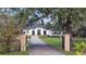 White two-story house with gated entry, manicured lawn, and mature trees at 15125 Waterline Rd, Bradenton, FL 34212