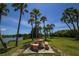 Picnic table and benches under palm trees near a calm waterway at 1523 46Th E Ave, Ellenton, FL 34222